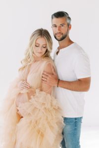 man hugs husband during fashion inspired studio maternity session
