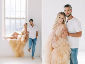 woman in peach gown poses in window with husband during studio maternity session