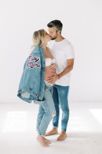 couple kisses while woman holds custom jean jacket over shoulder