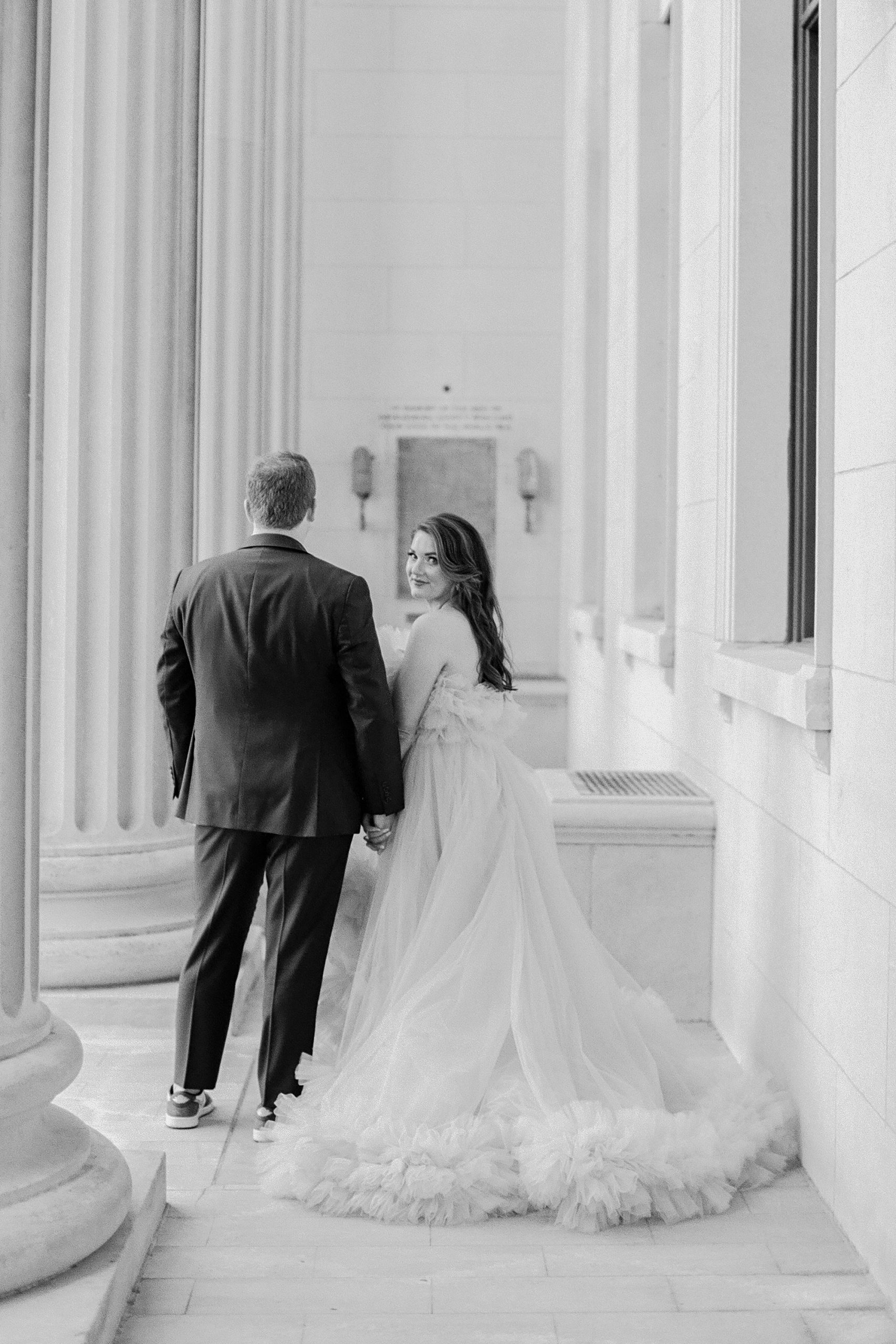 engaged couple walks down hallway of courthouse with woman looking over shoulder