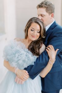 woman hugs man's arm in navy suit during glam Charlotte engagement session