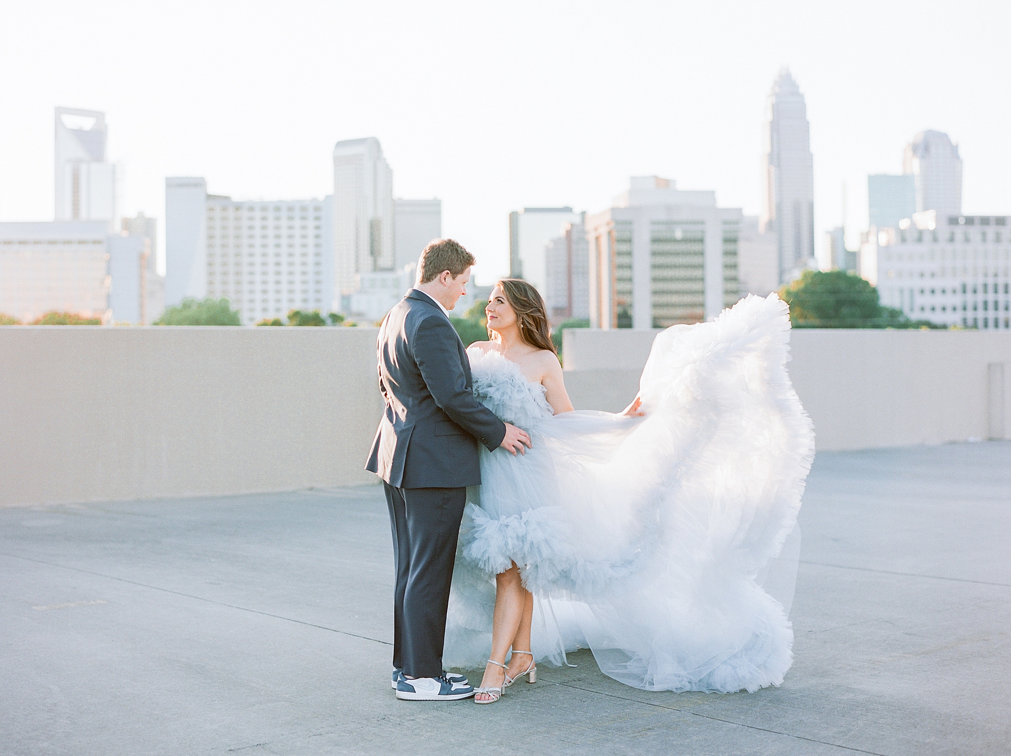 bride shows off skirt of blue dress during glamorous Charlotte engagement session