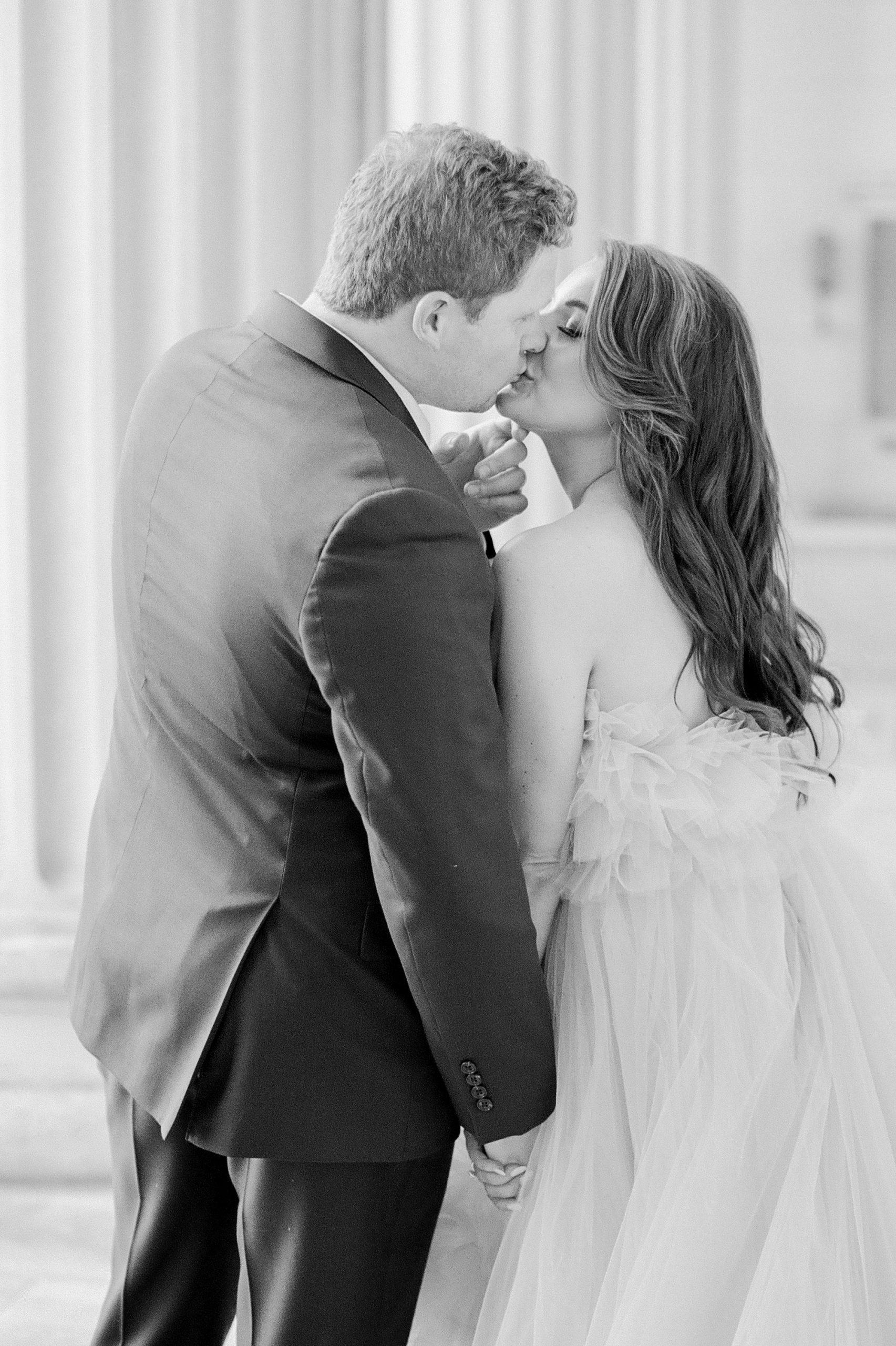 bride and groom kiss among columns of Charlotte courthouse