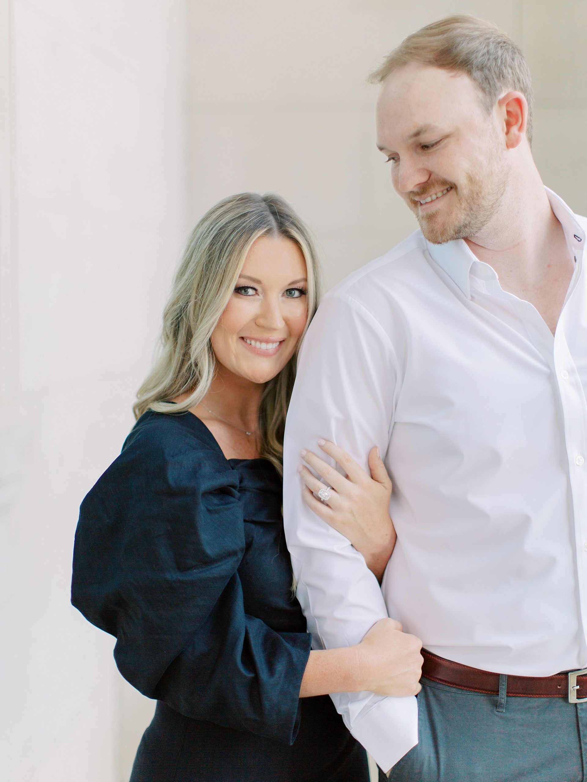 woman holds man's arm during Uptown Charlotte engagement session in building with marble walls