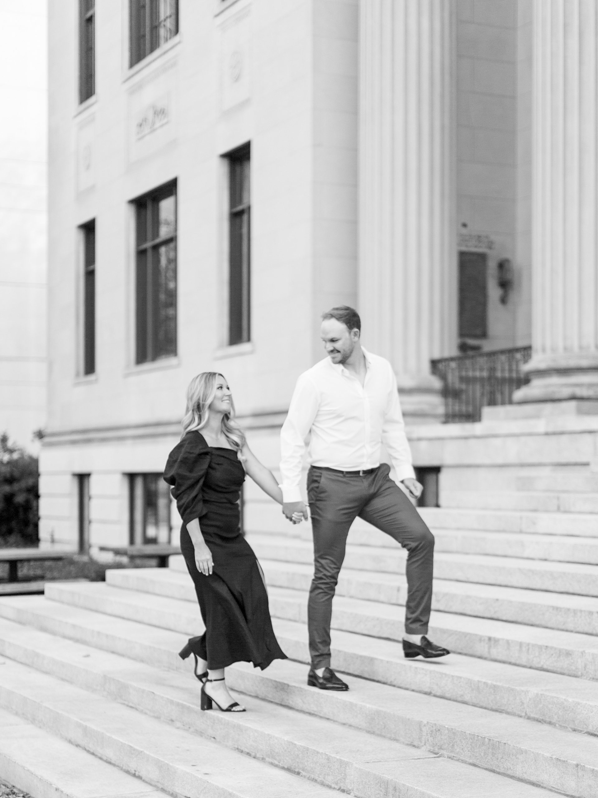 engaged couple walks up steps during Uptown Charlotte engagement session