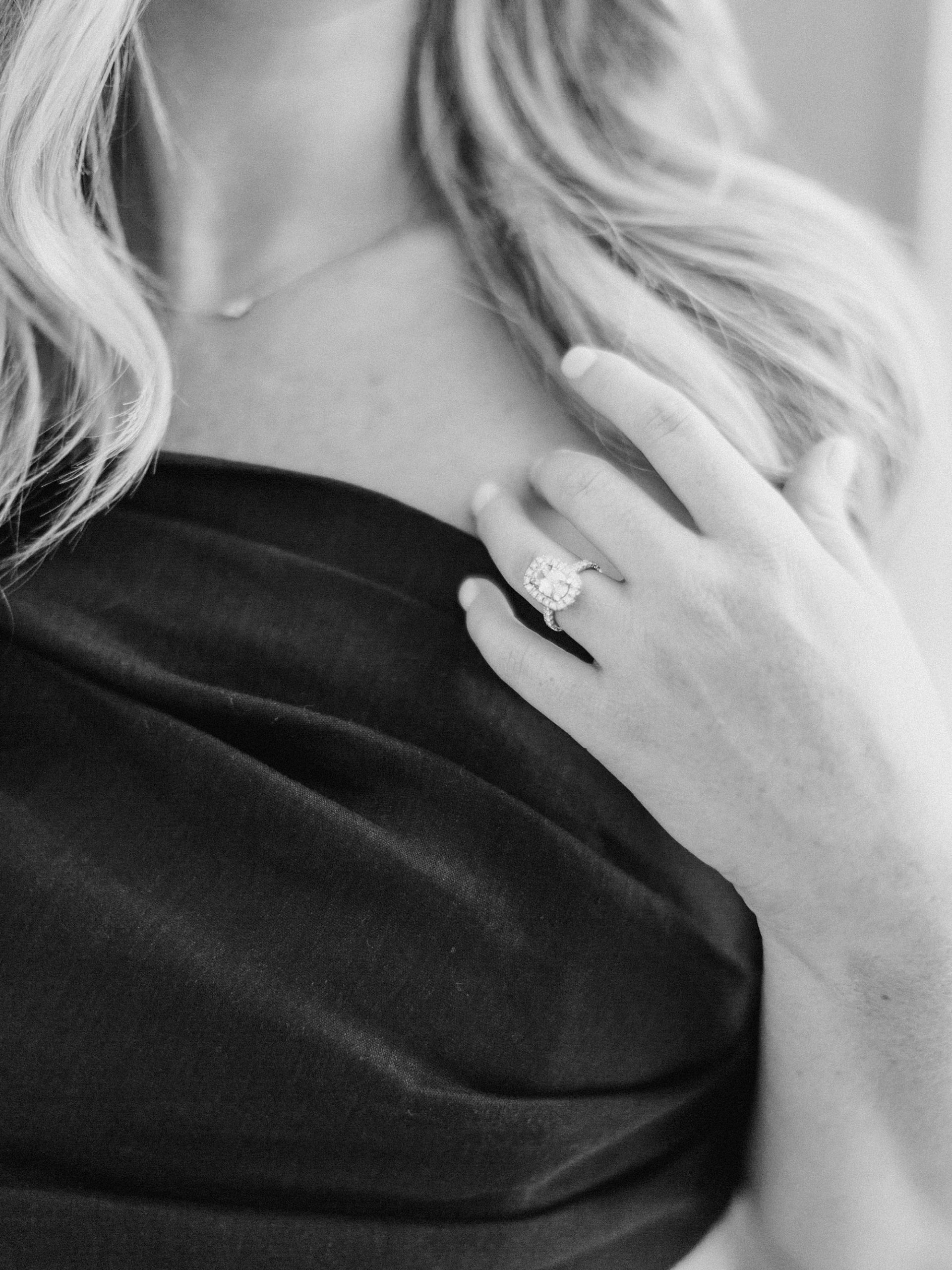 woman pushes hair off shoulder showing off engagement ring