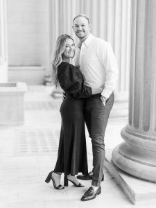engaged couple poses by pillar during Uptown Charlotte engagement session