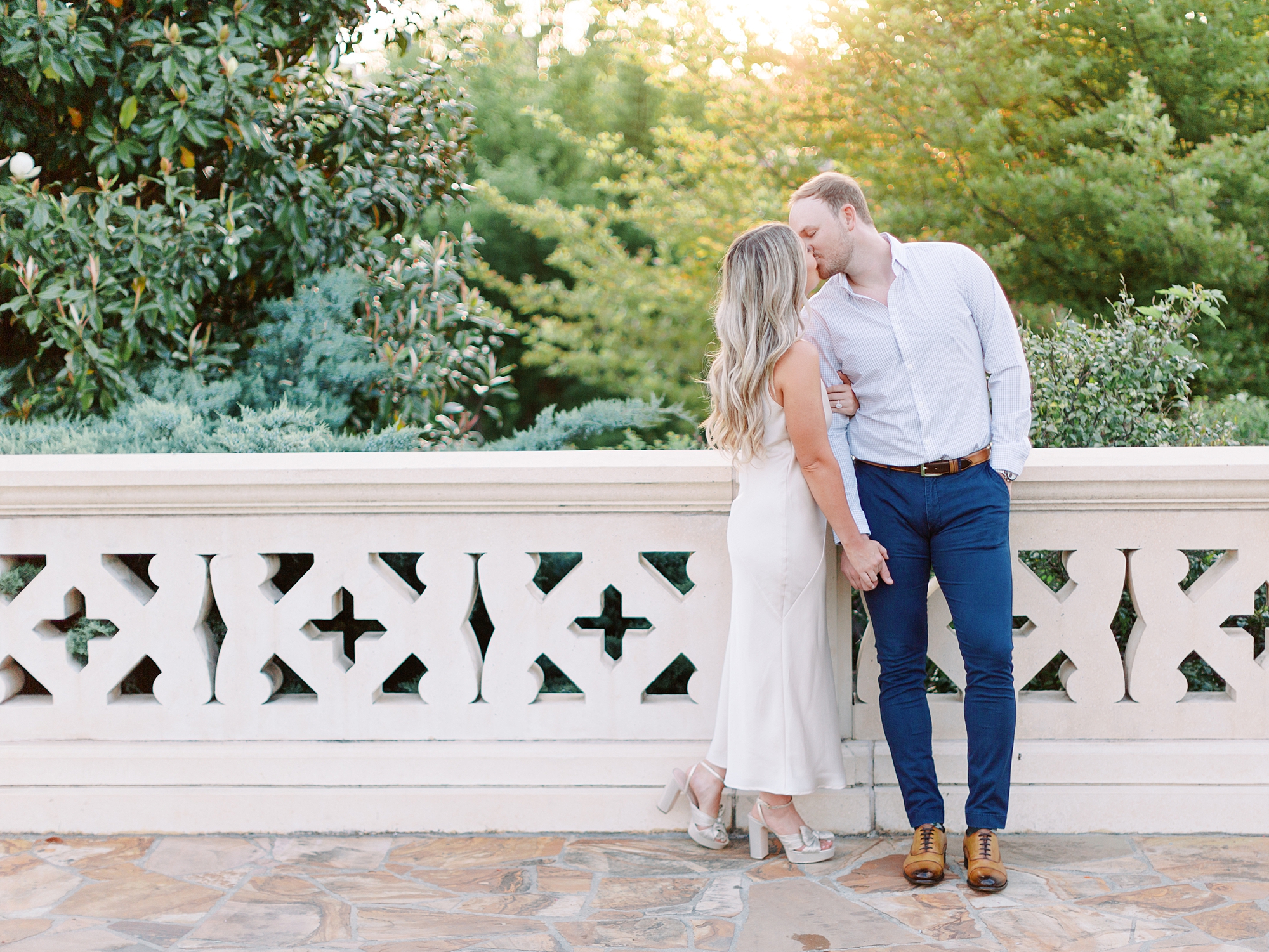 engaged couple kisses on bridge in park during Uptown Charlotte engagement session