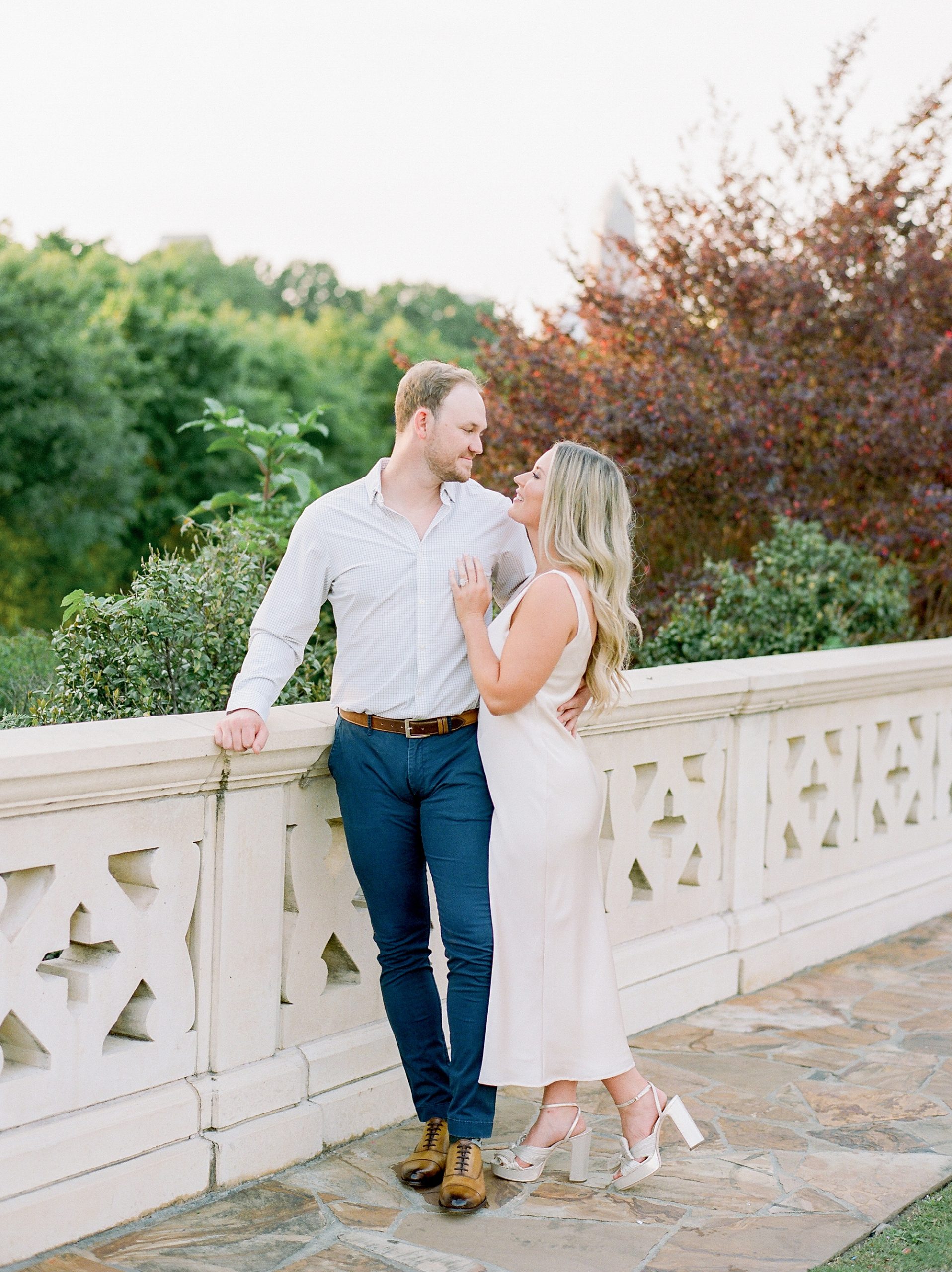 engaged couple poses on bridge during Uptown Charlotte engagement session