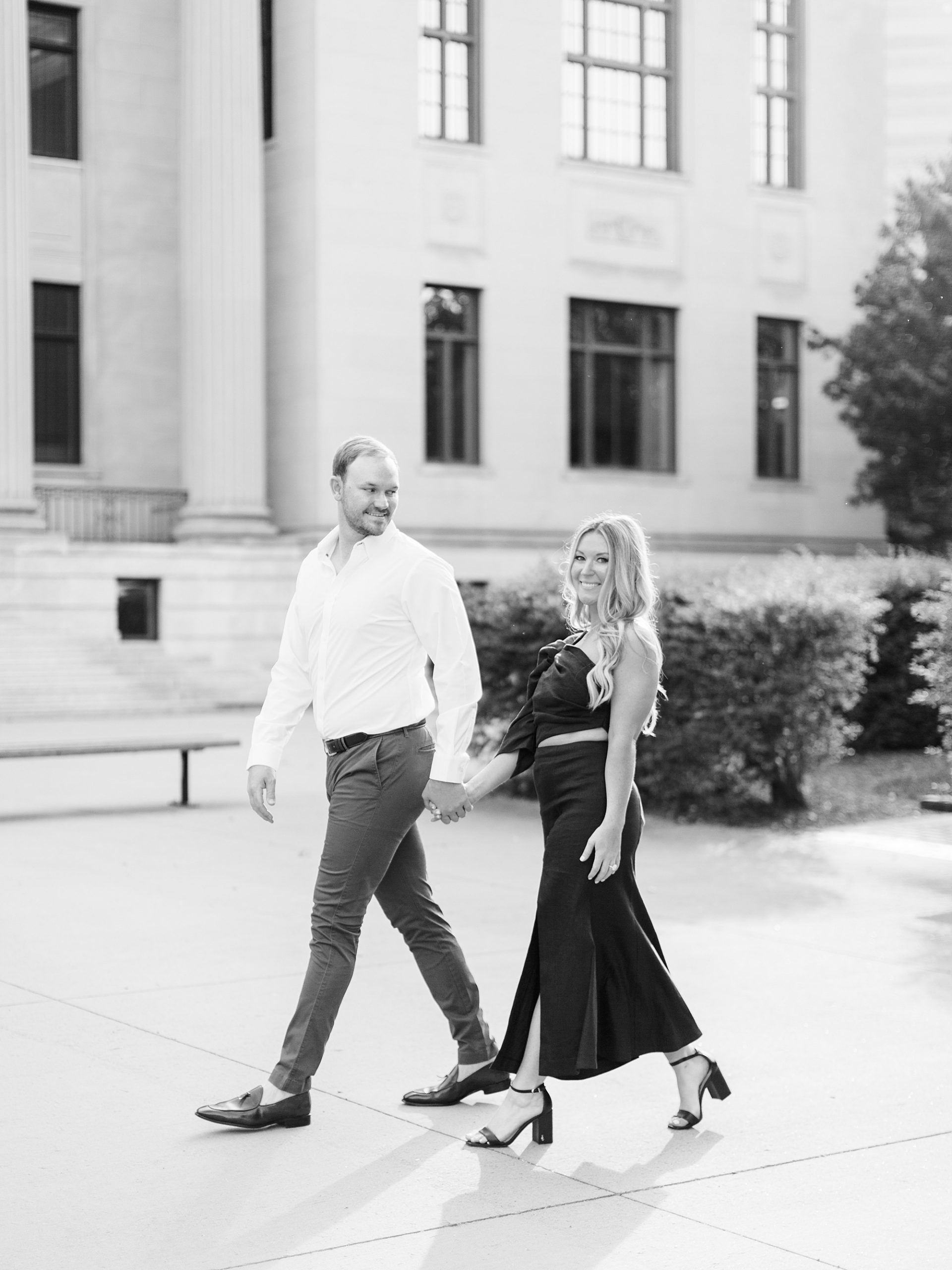 engaged couple holds hands walking during Uptown Charlotte engagement session