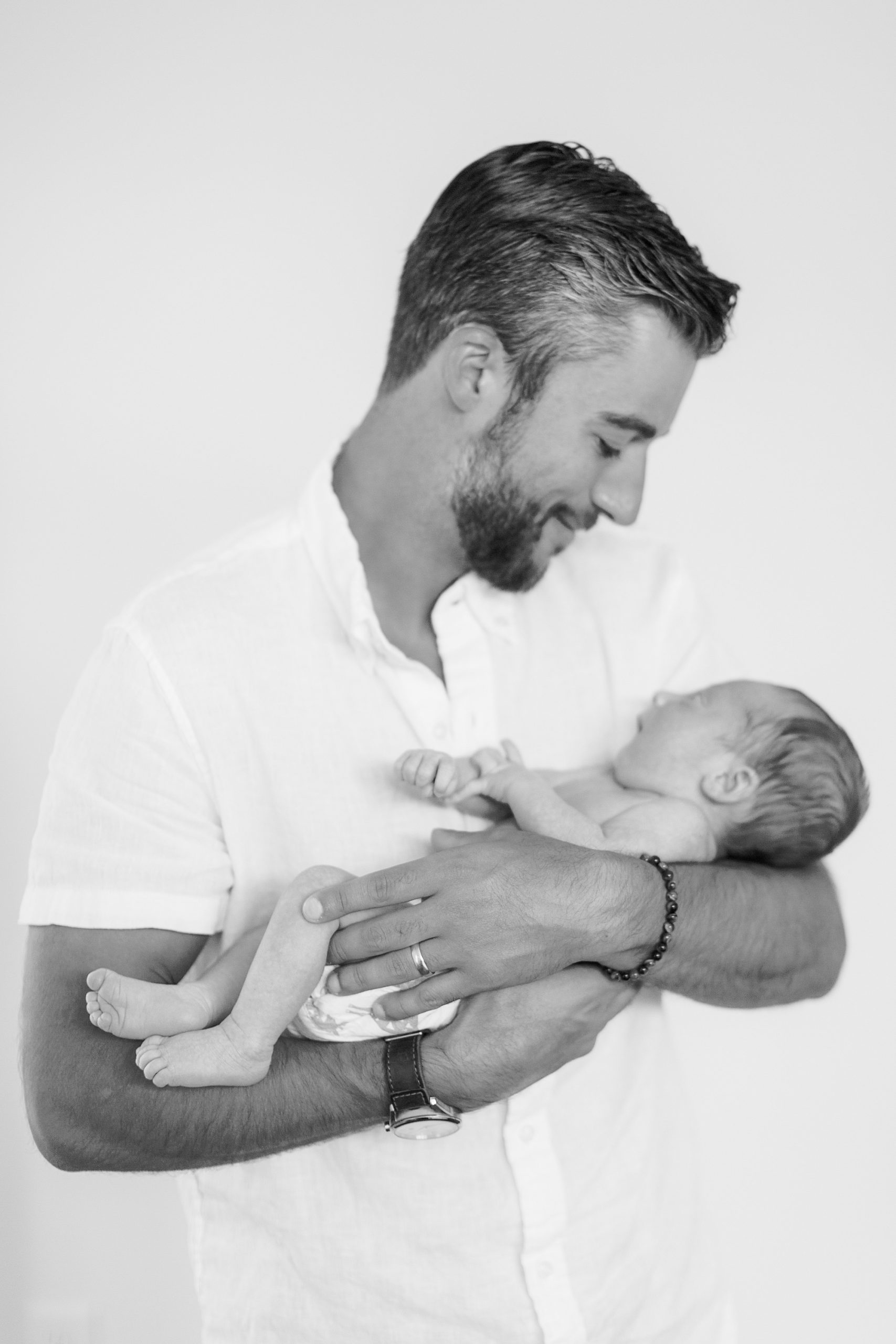 dad looks down at son in arms during Charlotte lifestyle newborn session