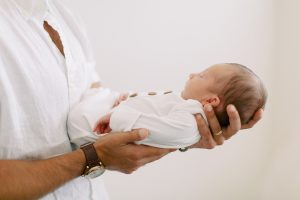 dad holds newborn baby boy against chest