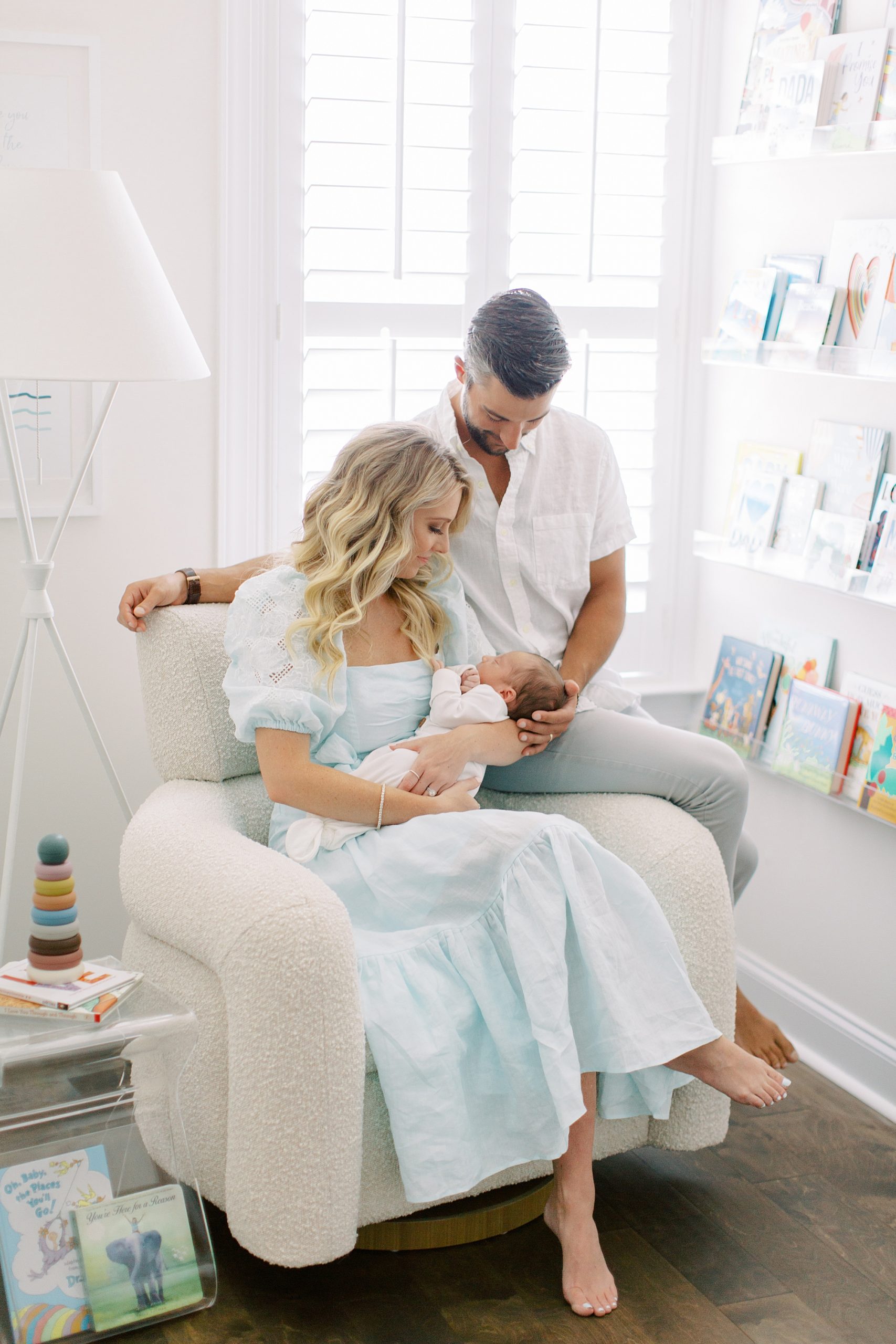 new parents look down at baby boy in rocker during Charlotte lifestyle newborn session