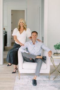 husband and wife team sit together in living room during Charlotte branding portraits for construction company