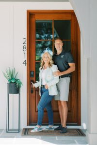 couple poses by front door of custom home