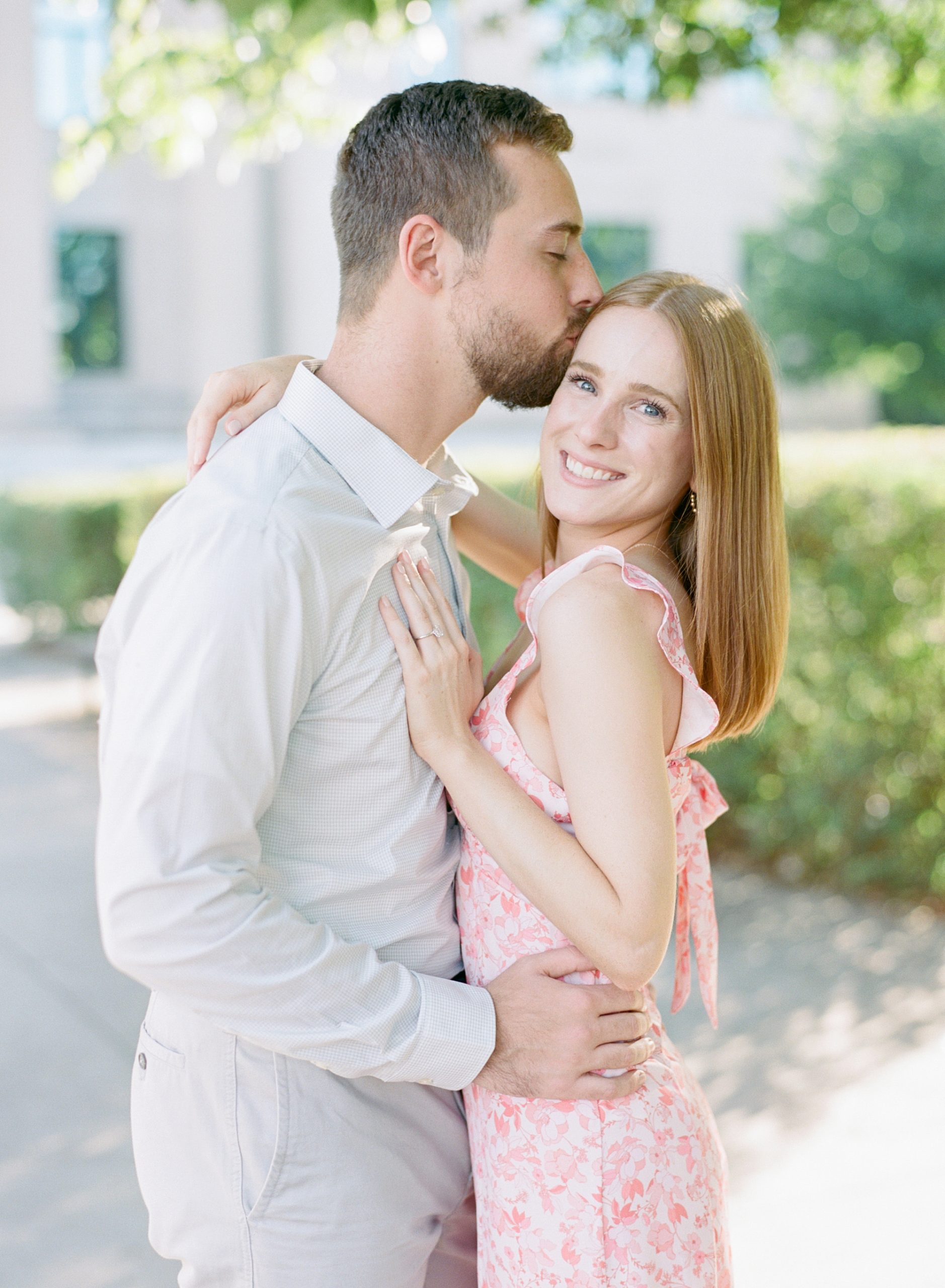 groom kisses bride's forehead during stylish Uptown Charlotte engagement session