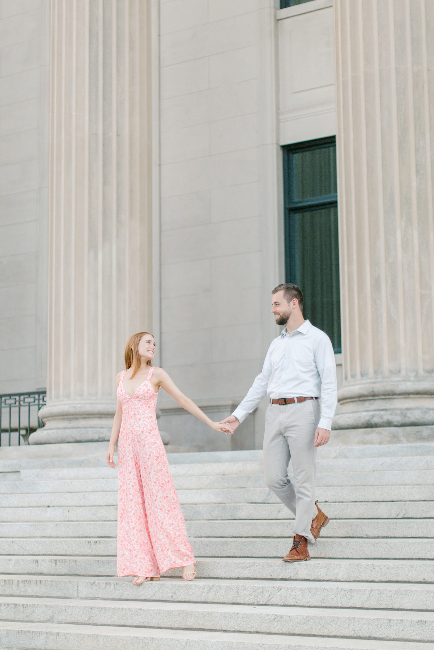 bride and groom hold hands walking down steps during Uptown Charlotte engagement photos