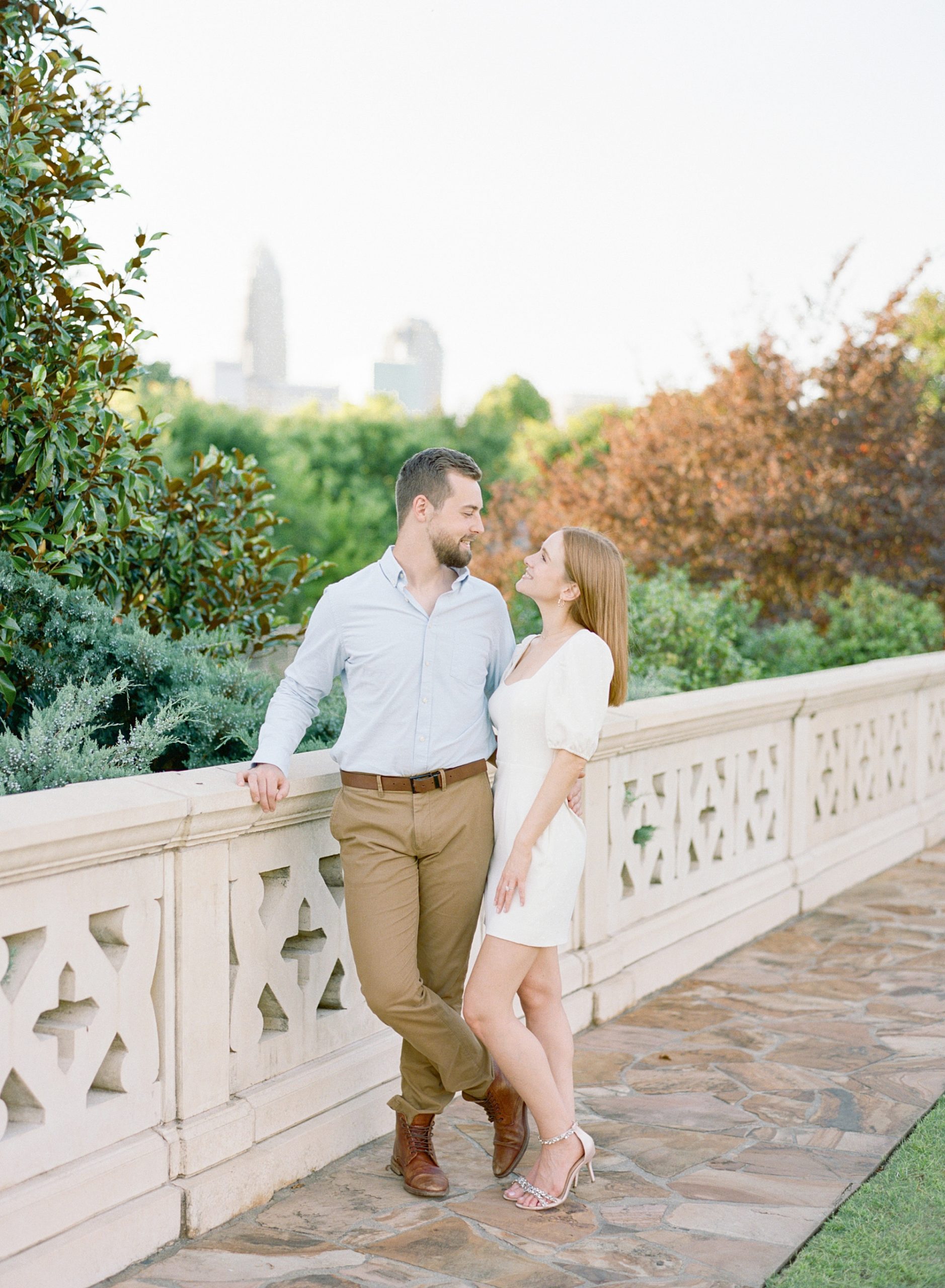 bride and groom stand smiling at each other leaning against bridge in Charlotte NC