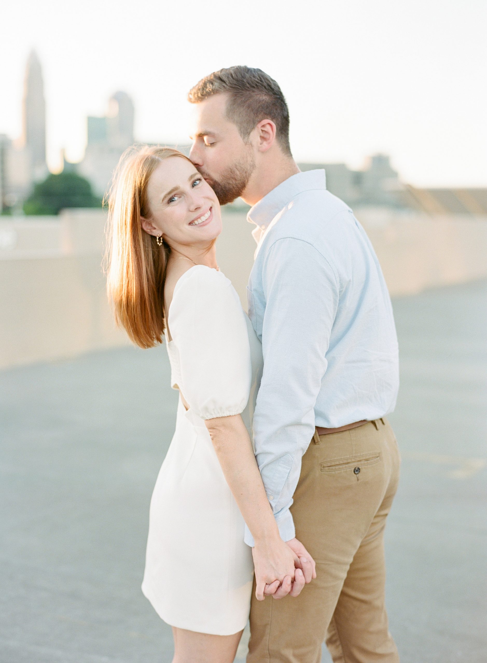 groom kisses bride's cheek on rooftop in Uptown Charlotte