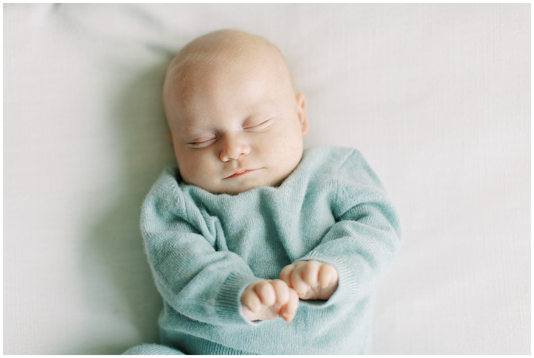 baby boy sleeps in teal sweater during Charlotte in-home newborn session