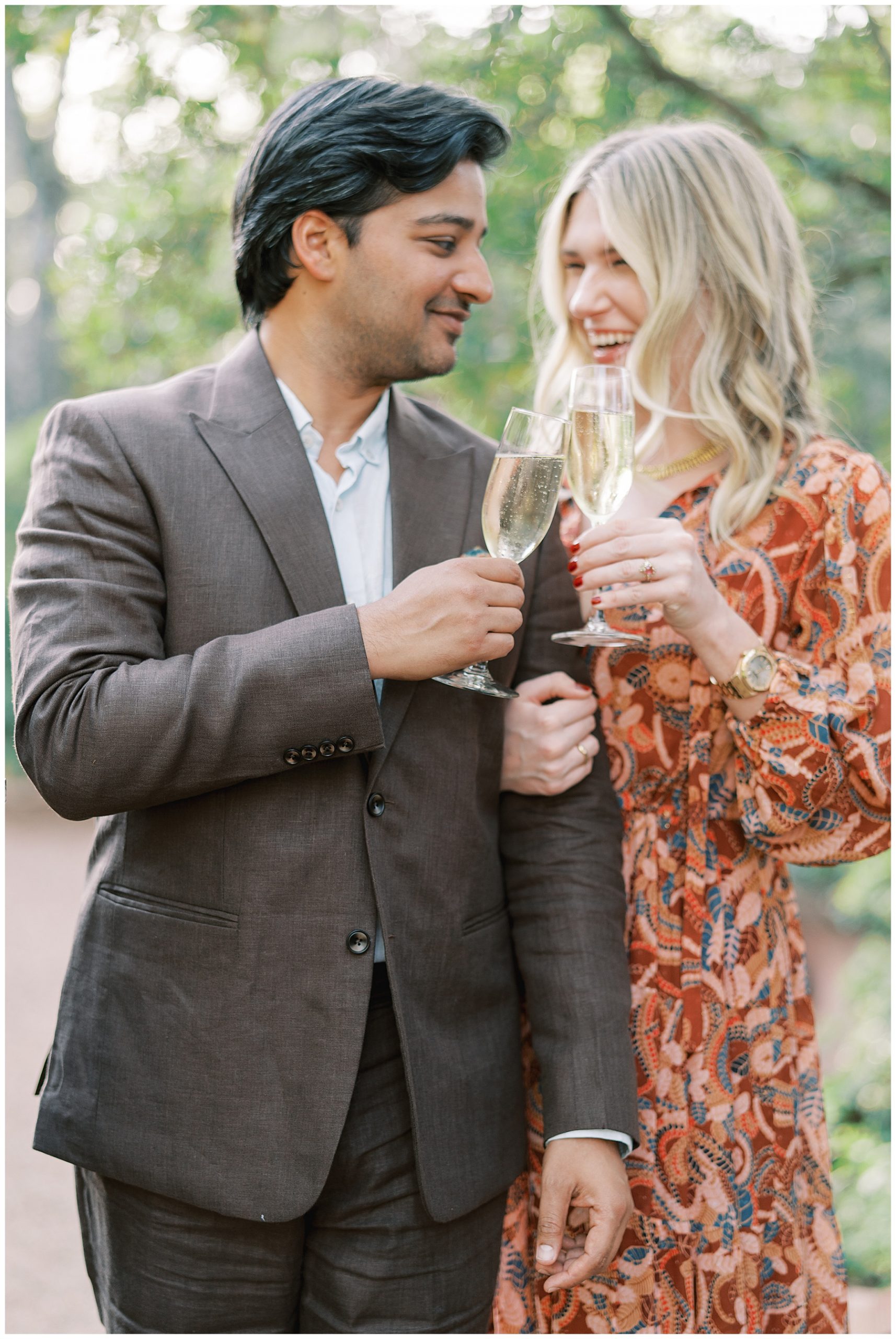 engaged couple laughs toasting glasses of champagne during Duke Mansion engagement session