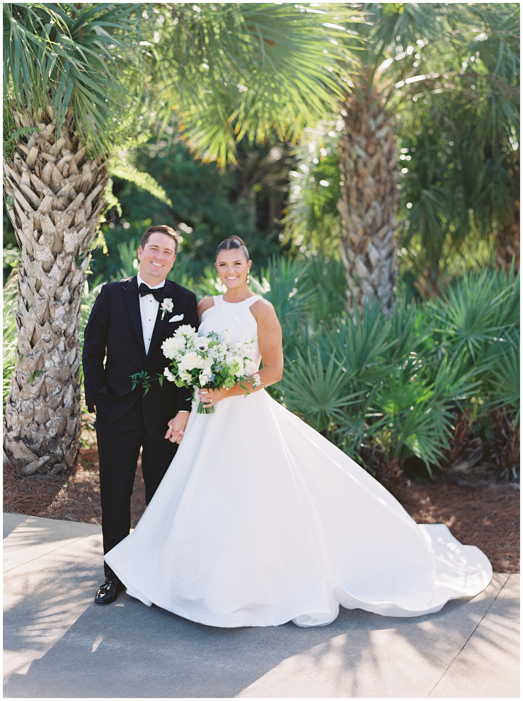 bride and groom hold hands by palm trees in Florida 