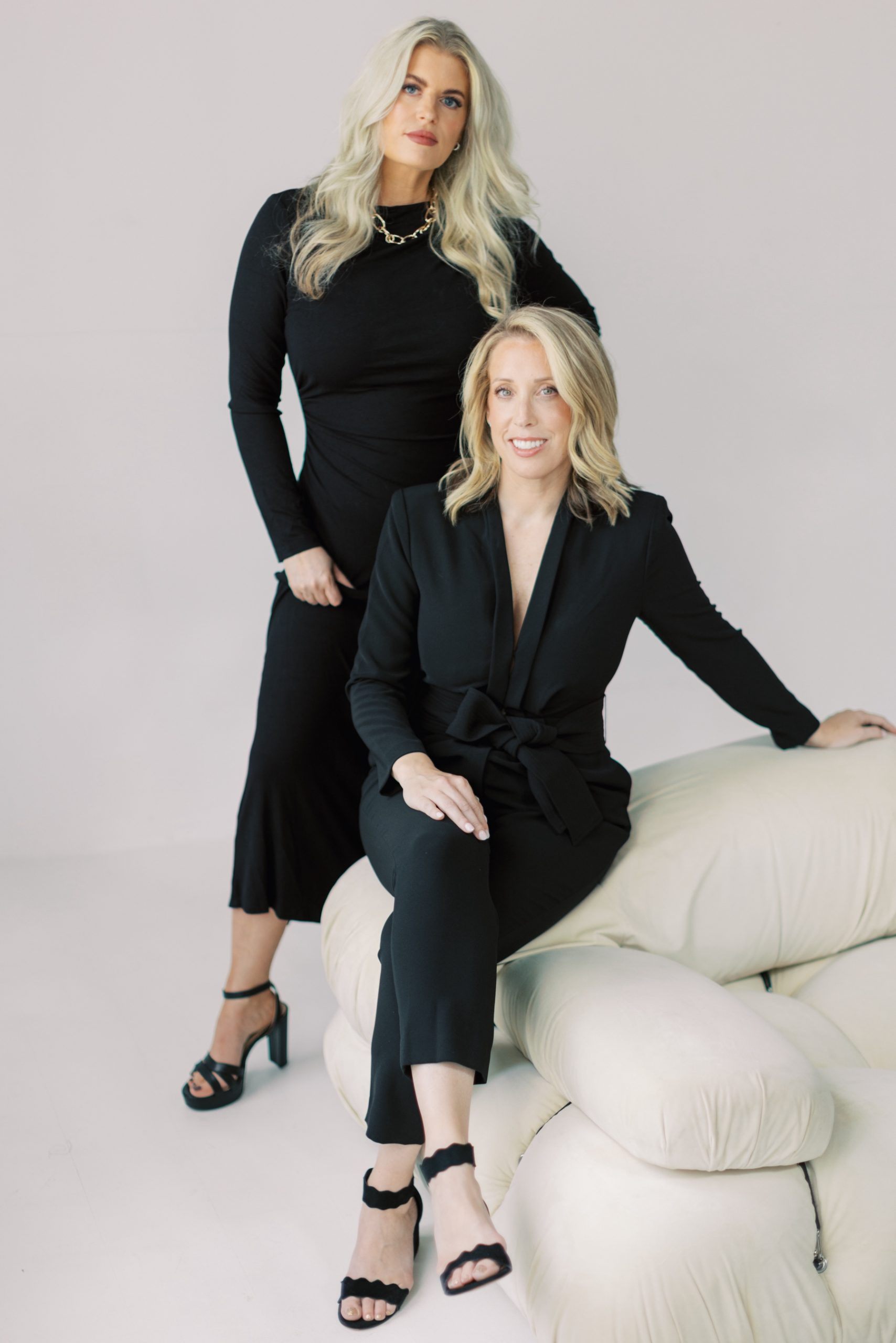 two blonde women pose by sofa in Atlanta studio during wedding planners branding session