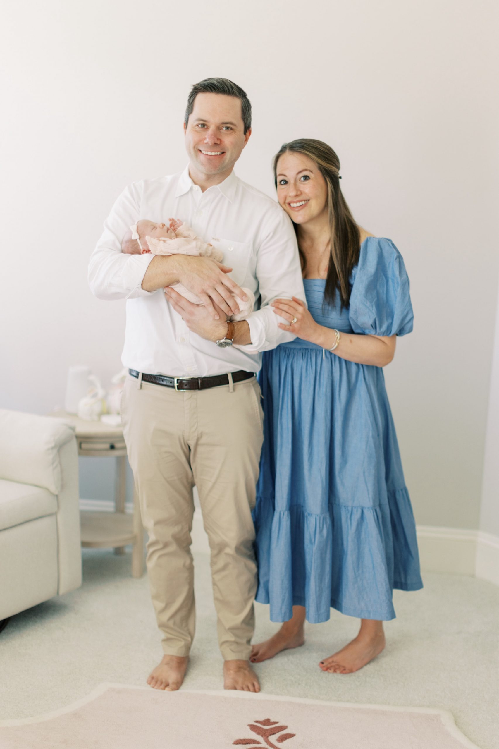 parents smile holding newborn daughter during newborn session In Charlotte home nursery