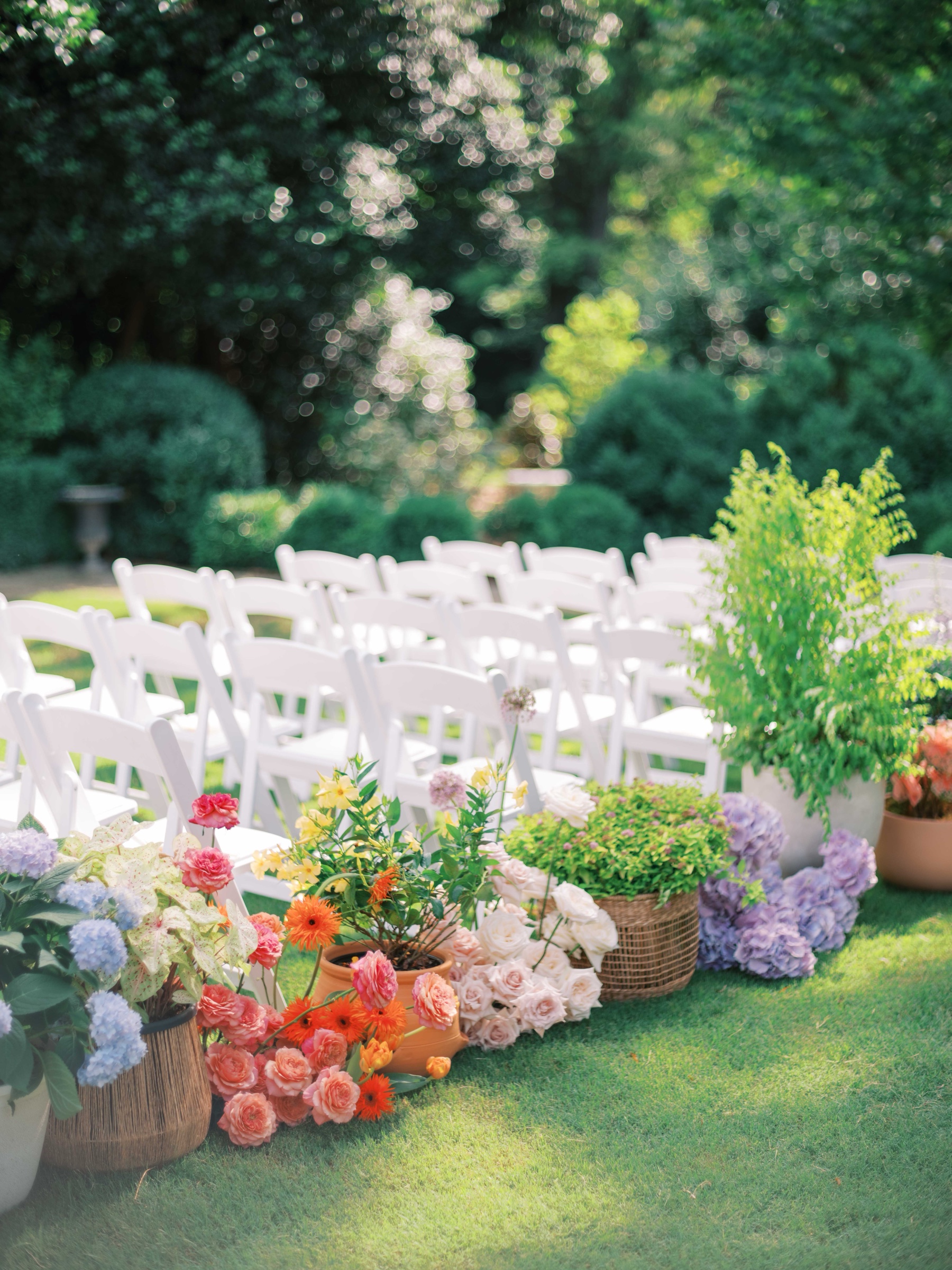 colorful spring flower buckets line aisle next to white chairs for Duke Mansion wedding day