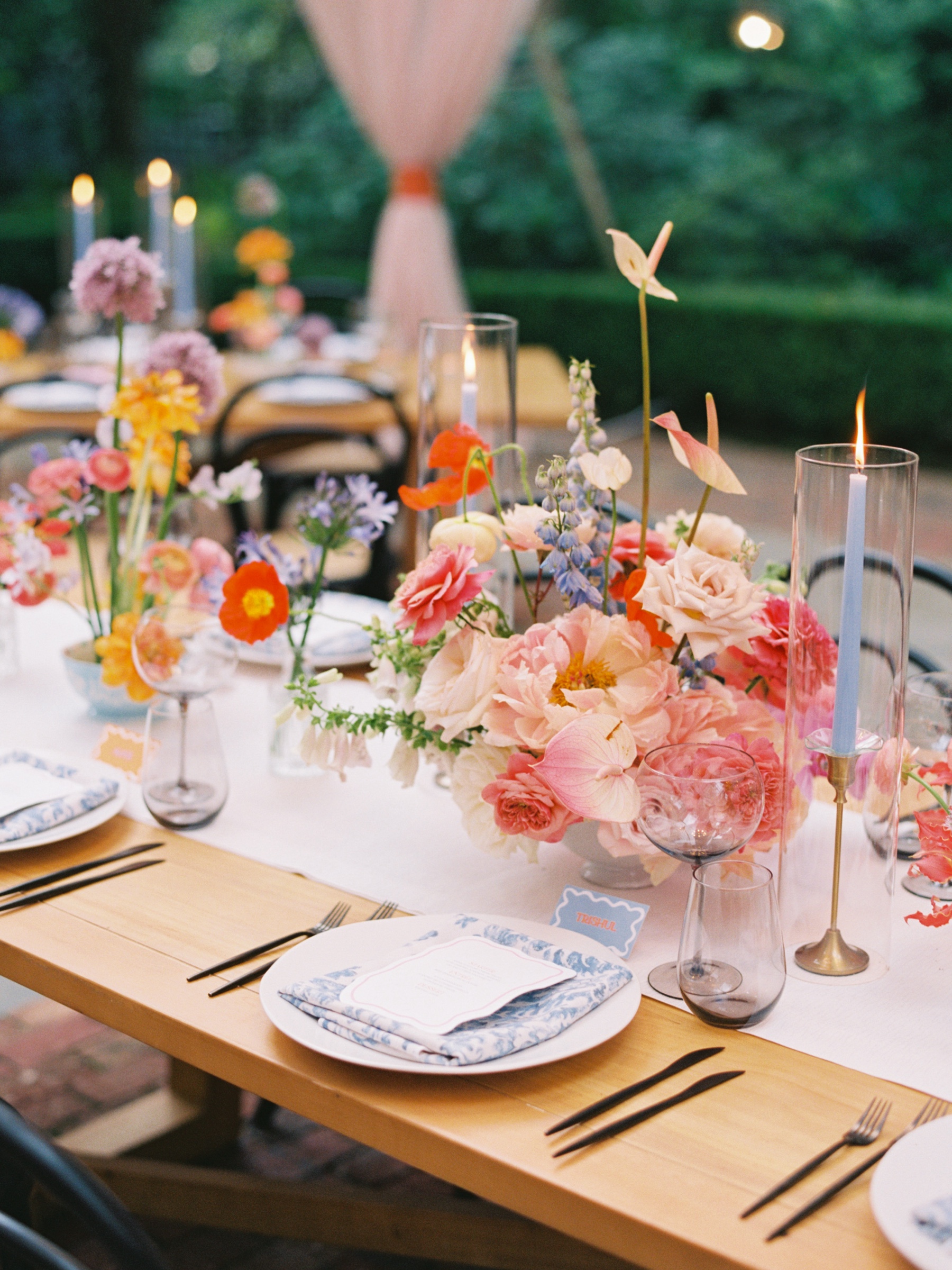 bright floral centerpiece with pale blue taper candles with blue and white napkins for Duke Mansion wedding reception 