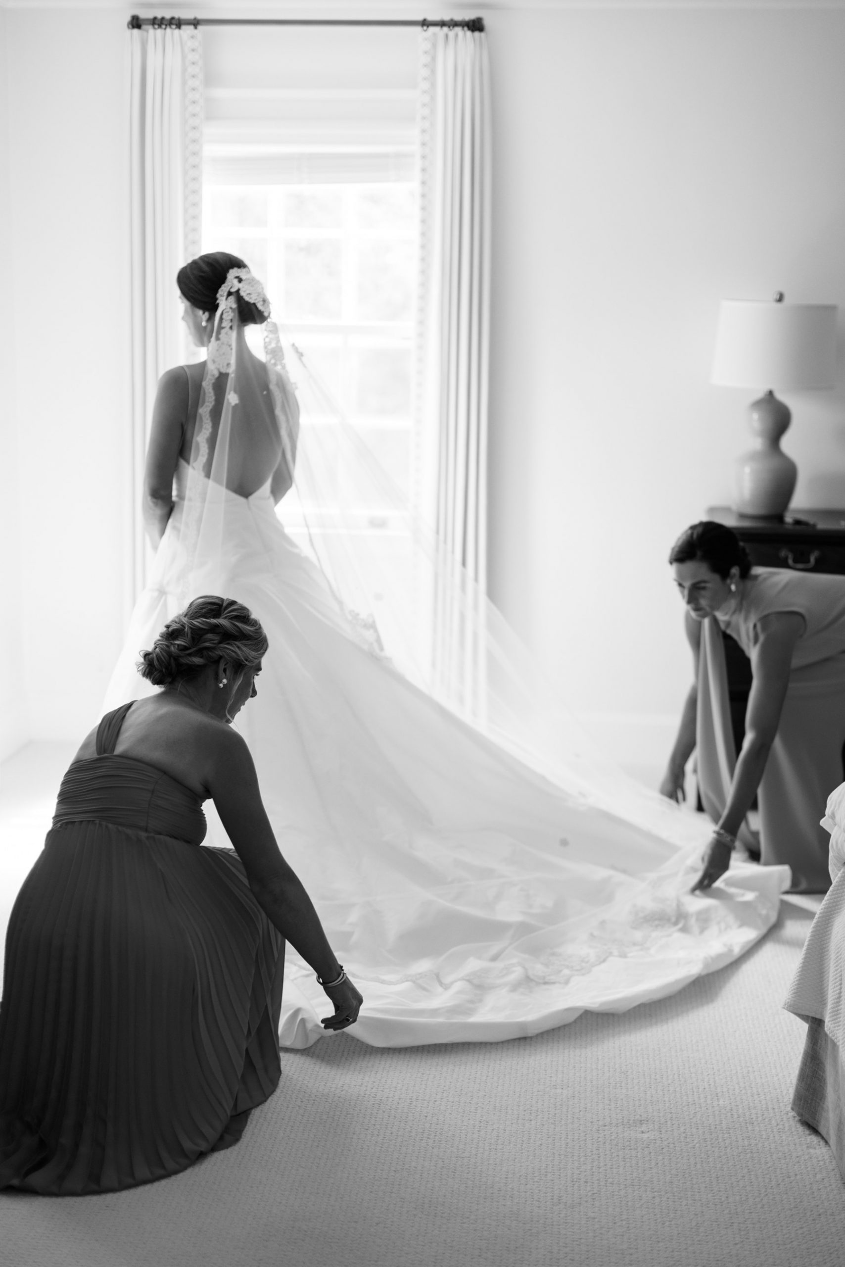 Timeless wedding photo of bride getting into wedding dress with the help of bridesmaids