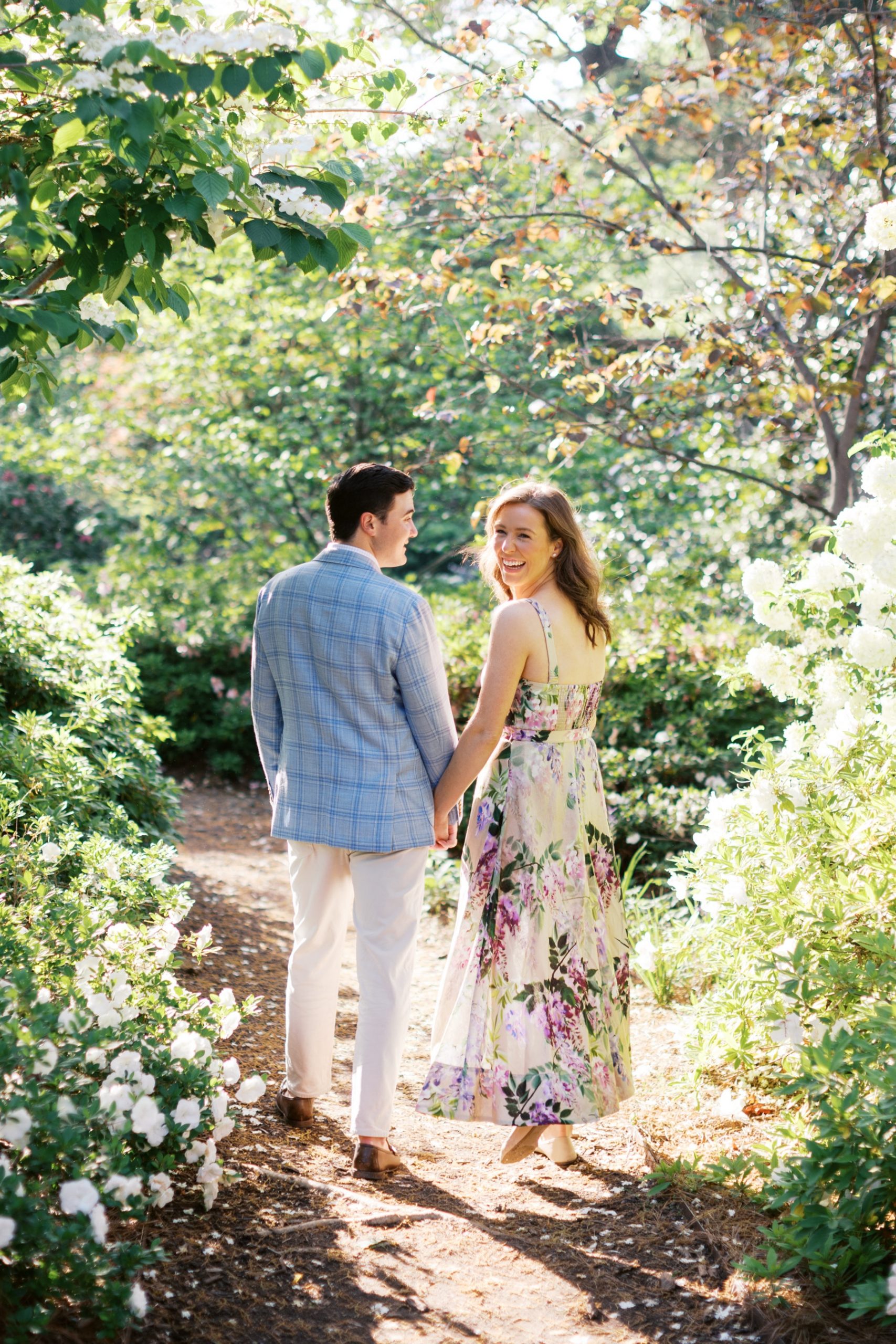 engaged couple walk down path together holding hands